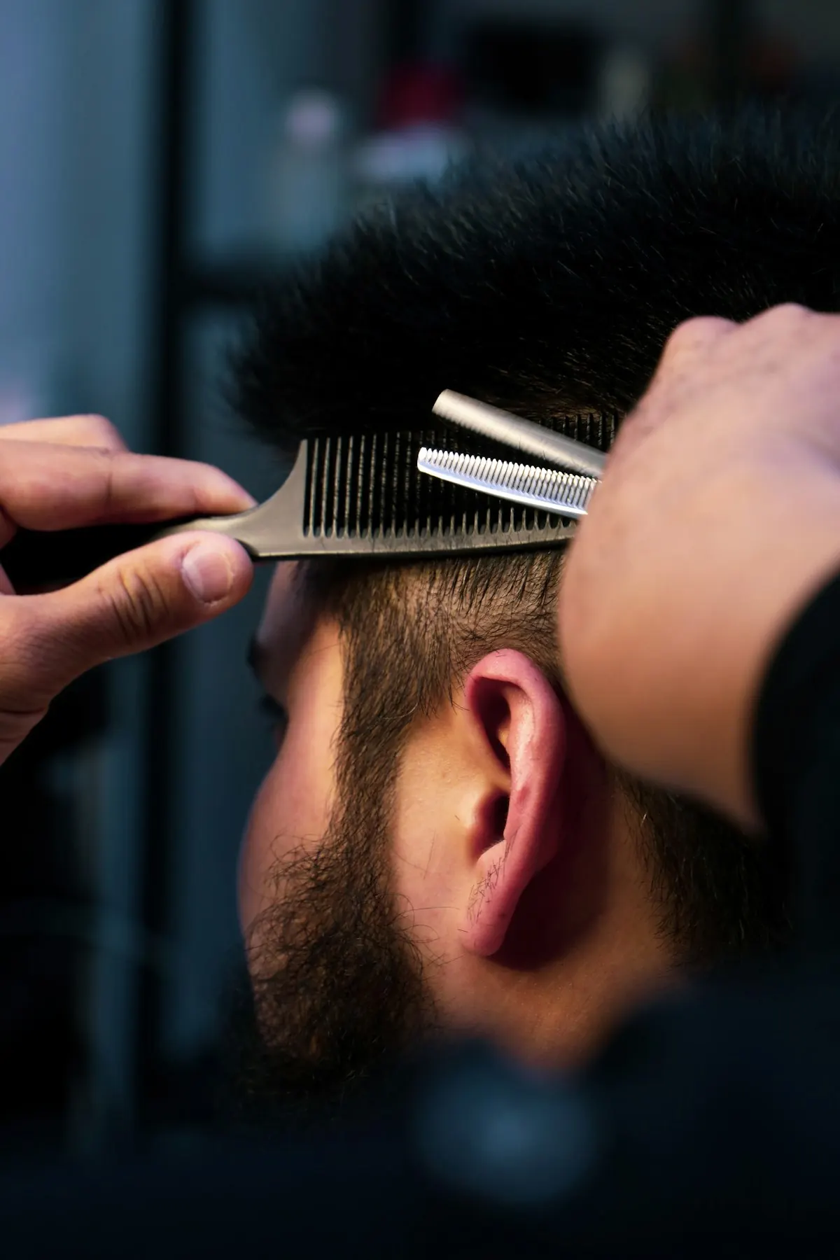 Barbeiro cortando cabelo com pente e tesoura